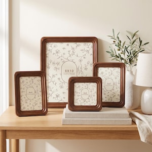 May include: Four dark brown wooden photo frames with rounded corners, featuring cream-coloured inserts with a delicate black floral line drawing pattern. The frames are labelled with their respective sizes: 4x6, 8x10, 4x4, and 5x7 inches.