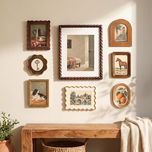 May include: A gallery wall arrangement featuring seven framed artworks. The collection includes a silver teapot, a vintage key, a dog, a room interior, a stone bridge landscape, a staircase, a horse, and peaches, all displayed in various wooden frames.