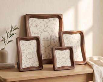 May include: A set of four dark brown wooden photo frames with wavy, contoured edges. The frames contain white inserts with a delicate floral line drawing pattern and printed text indicating sizes 8x10, 4x6, 5x7, and 4x4 photo frame.