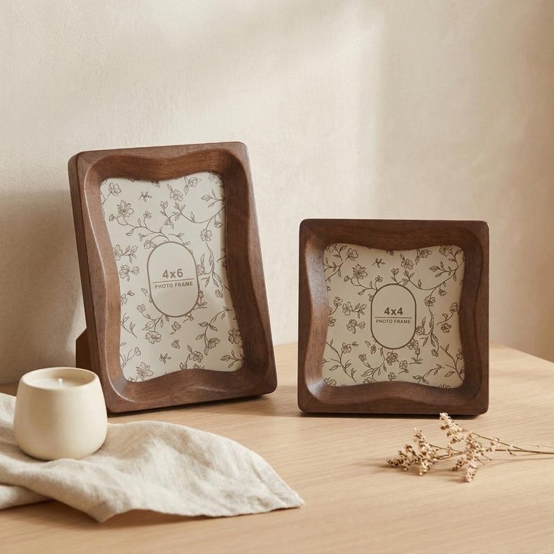 May include: Two dark brown wooden photo frames with wavy edges. The left frame contains a paper insert labeled 4x6 PHOTO FRAME, and the right frame contains a paper insert labeled 4x4 PHOTO FRAME. Both inserts feature a delicate floral line drawing.