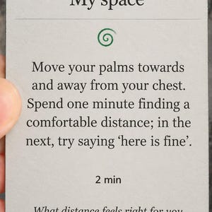 May include: A rectangular light gray card with rounded corners featuring the text EYES OPEN, My space, and instructions to move palms towards and away from the chest. It includes a green spiral icon, the text 2 min, and the question What distance feels right for you today?