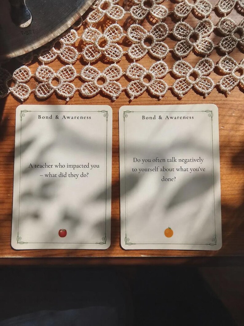 May include: Two rectangular cards with the heading Bond & Awareness. The left card asks, A teacher who impacted you - what did they do? with a small red apple icon. The right card asks, Do you often talk negatively to yourself about what you've done? with a small orange icon.