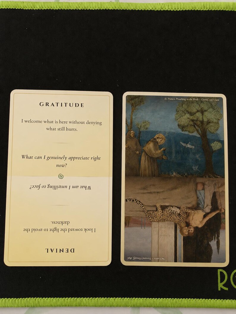 May include: Two rectangular cards with rounded corners. The left card is cream-colored with the text GRATITUDE and DENIAL, featuring reflective questions. The right card displays two inverted paintings: St. Francis Preaching to the Birds and The Caress.