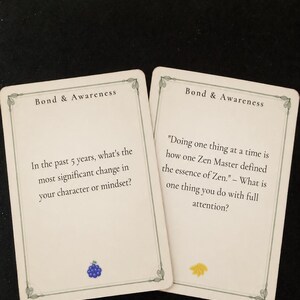 May include: Two off-white rectangular cards titled Bond & Awareness. The left card asks, In the past 5 years, what's the most significant change in your character or mindset? with a blue grape icon. The right card features a quote about Zen.