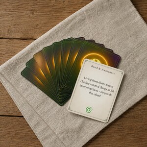 May include: A deck of cards fanned out, with the top card featuring the text Bond & Awareness, followed by the sentence Living from desire means chasing external things to fill inner emptiness &ndash; do you do this often? and a green spiral icon.