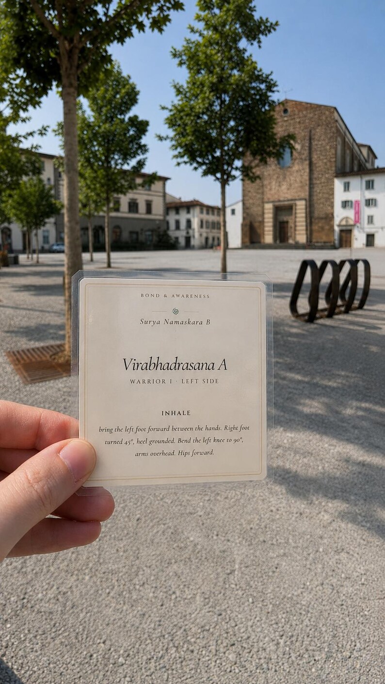 May include: A rectangular, cream-colored instructional card encased in a clear plastic sleeve. The text reads: BOND & AWARENESS, Surya Namaskara B, Virabhadrasana A, WARRIOR I LEFT SIDE, INHALE, bring the left foot forward between the hands.