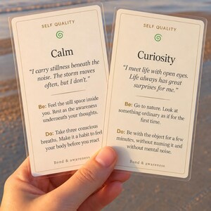 May include: Two rectangular off-white cards with rounded corners, each titled Self Quality. The left card features the word Calm and text about stillness. The right card features the word Curiosity and text about meeting life with open eyes. Both cards include Be and Do prompts.