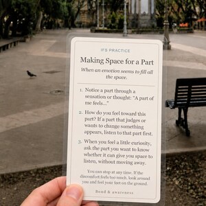 May include: A rectangular, semi-transparent card with rounded corners featuring black text on a cream background. The card is titled IFS PRACTICE Making Space for a Part and provides three numbered steps for emotional regulation and awareness.