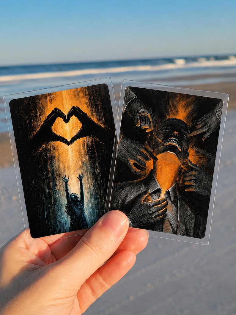 May include: Two rectangular art cards in clear protective sleeves. The left card shows a silhouette of a person reaching toward a glowing heart shape formed by hands. The right card depicts a person surrounded by multiple hands with orange light.