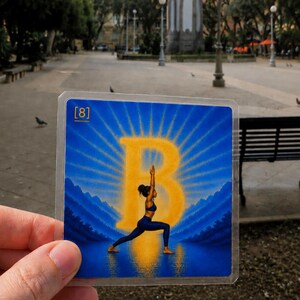 May include: A square card featuring a blue and yellow illustration of a person in a yoga pose centered in front of a large letter B. The background shows blue mountains and a sunburst pattern. The text [8] is printed in the top left corner.
