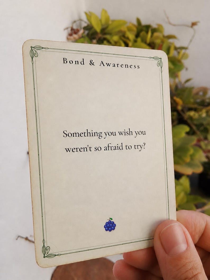 Op de afbeelding: Een rechthoekige gebroken witte kaart met een dunne groene rand en decoratieve hoeken. De tekst luidt bovenaan Bond & Awareness en in het midden Something you wish you weren't so afraid to try?. Onderaan staat een klein blauw druivenicoon.