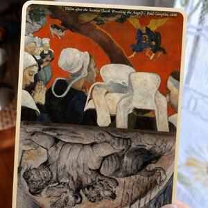 May include: A rectangular card featuring two distinct art prints. The top section displays Paul Gauguin's Vision after the Sermon, showing figures in white bonnets against a red background. The bottom section shows William Blake's Cerberus.