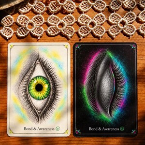 May include: Two rectangular oracle cards labeled Bond & Awareness. The left card features an open eye with a green and yellow iris on a white background. The right card shows a closed eye with long lashes surrounded by a vibrant pink and green aura on a black background.