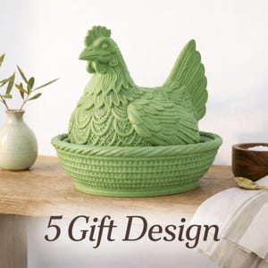 Könnte beinhalten: Ein grüner Keramikbehälter in Form eines Huhns mit einem korbartigen Sockel. Das Huhn hat detaillierte Feder- und spitzenartige Muster. Eine kleine Vase mit Grünzeug, eine Holzschale und ein goldener Löffel befinden sich ebenfalls auf der Holzoberfläche. Der Text "5 Gift Design" steht unten.