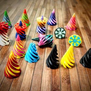 May include: A selection of brightly coloured, abstract 3D-printed sculptures. The pieces display spiral and conical forms in vivid hues such as red, yellow, blue, and green. Some have striped patterns, while others are solid.