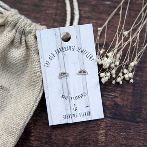 May include: A pair of sterling silver earrings featuring a crescent moon design. The earrings are presented on a white card with the text "The Old Farmhouse Jewellery" and "Made in Cornwall".