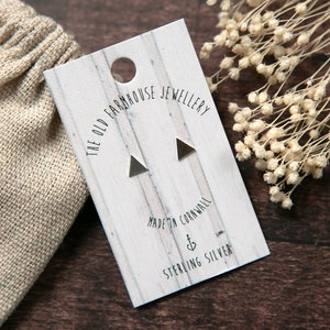 May include: A pair of sterling silver triangle stud earrings on a white card with the text "The Old Farmhouse Jewellery Made in Cornwall Sterling Silver".