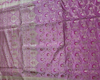 May include: A light purple fabric featuring an intricate woven pattern of silver metallic floral motifs and vibrant magenta circular flower accents. The textile includes a wide border with detailed silver paisley and leaf designs.