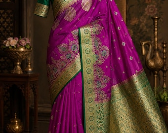 May include: A vibrant magenta saree featuring intricate gold and green zari embroidery throughout the fabric. The garment includes a wide, ornate gold border with floral motifs and a solid green blouse with matching gold trim on the sleeves.