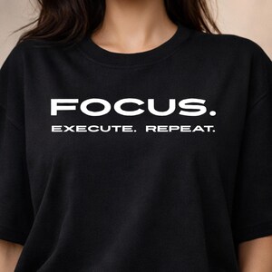 May include: Black crew neck sweatshirt with the white text "FOCUS. EXECUTE. REPEAT." The sweatshirt is worn by a person with dark hair and gold hoop earrings.