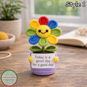 Può includere: Un fiore all'uncinetto fatto a mano in un vaso viola con la scritta "Today is a good day for a good day." Il fiore ha petali colorati e una faccia sorridente. Il vaso ha manici gialli. L'immagine include anche il testo "Style 1".