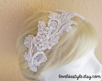 May include: White lace headband with pearl accents. The headband is delicate and feminine, perfect for a wedding or special occasion.