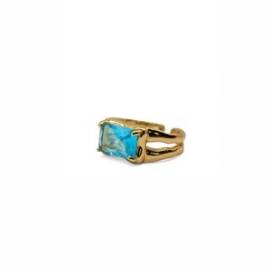 Könnte beinhalten: Ein goldfarbener Ring mit einem großen, rechteckigen, hellblauen Edelstein. Der Ring hat ein Doppelband-Design, wobei der Edelstein in einem quadratischen Rahmen gefasst ist. Der Ring ist vor einem weißen Hintergrund platziert.
