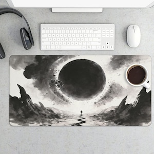 May include: A black and white mouse pad featuring a surreal landscape with a large dark sphere in the sky. A lone figure stands on a cracked path. A white coffee mug with dark coffee sits on the pad.