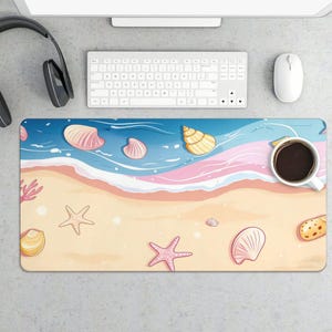 May include: A rectangular desk mat featuring a beach scene with seashells, starfish, and waves. The mat has a light tan sand color, blue and pink water, and a white coffee cup. A keyboard, mouse, and headphones are also visible.