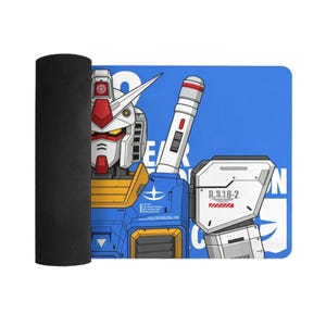 K&ouml;nnte beinhalten: Ein blau-wei&szlig;es rechteckiges Mauspad mit einer detaillierten Illustration eines Roboter-Kopfes und -Arms. Der Roboter hat rote, wei&szlig;e, blaue und gelbe Akzente. Das Mauspad ist auf der linken Seite aufgerollt und zeigt eine schwarze Unterseite.