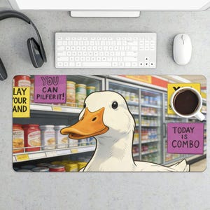 May include: A white duck illustration on a desk mat with a grocery store background. The mat has text that reads "You can pilfer it!" and "Today is combo." A cup of coffee sits on the mat.