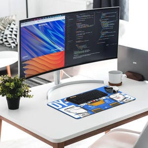 K&ouml;nnte beinhalten: Ein moderner Schreibtisch mit einem gebogenen Computermonitor, der Webdesign und Code anzeigt. Ein blau-wei&szlig;es Mauspad mit grafischem Design, eine schwarze Tastatur und eine wei&szlig;e Tasse befinden sich auf dem Schreibtisch. Eine kleine Topfpflanze sorgt f&uuml;r einen Hauch von Gr&uuml;n.