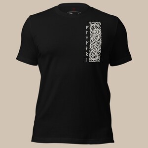 May include: Black t-shirt with a white, vertical design on the right side, featuring intricate knotwork and runes. The design is a detailed, symmetrical pattern. The shirt has short sleeves and a crew neck.