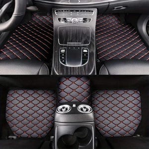 Puede incluir: Alfombrillas negras para coche con un patrón de diamantes y costuras rojas. Las alfombrillas están diseñadas para adaptarse a los asientos delanteros y traseros de un vehículo. El interior del coche es visible, incluyendo el salpicadero y la consola central.