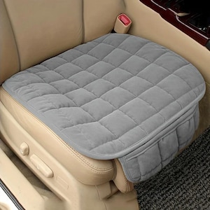 May include: A gray, quilted car seat cushion with a diamond pattern. The cushion is designed to fit over the existing car seat and has a side pocket. The seat is shown installed in a car with tan leather seats.