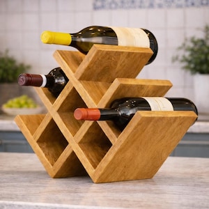 May include: A wooden wine rack holding three bottles of wine. The rack is made of light brown wood and has a diamond-shaped design. The wine bottles have different colored caps and labels.