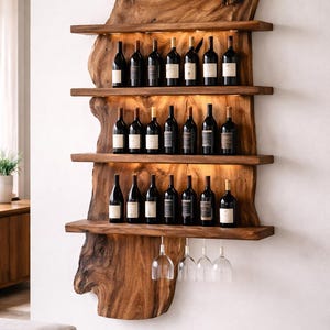 Puede incluir: Un botellero de madera rústico con cuatro estantes, que contiene numerosas botellas de vino. El botellero está montado en una pared blanca, con copas de vino colgando debajo. La madera tiene una forma natural y tonos marrones cálidos.