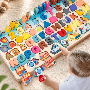 Peut inclure: Un plateau de puzzle éducatif en bois présentant des lettres de l'alphabet colorées, des chiffres, des formes géométriques et diverses illustrations de véhicules. Le plateau comprend des emplacements pour chaque pièce, avec des blocs en bois aux couleurs vives représentant les lettres de A à Z, des chiffres et des icônes de transport comme un train, un bateau et un camion de pompiers.