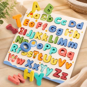 May include: A wooden alphabet puzzle board featuring colorful, chunky uppercase and lowercase letters. The board includes illustrations for each letter, such as an apple, bee, and ice cream. Several loose wooden letters are scattered around the board.