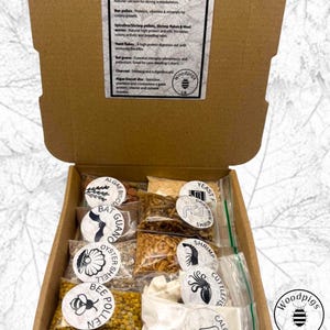 May include: A cardboard box containing various small, clear plastic bags filled with animal feed supplements. Each bag has a circular label identifying contents like bee pollen, shrimp pellets, charcoal, and dried mealworms. A printed information sheet is attached.