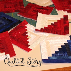 May include: A collection of red, white, and blue fabric squares with a log cabin pattern. The squares are arranged on a green cutting mat and a white surface. The text "The Quilted Story" is visible in the bottom center of the image.