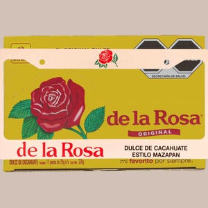 May include: A yellow box of "de la Rosa" peanut candy, featuring a large red rose graphic with green leaves. The box includes text in Spanish, including "Dulce de Cacahuate" and "mi favorito por siempre."
