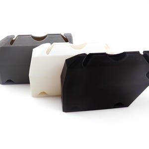 May include: A white ceramic mug with a black handle and the text "But First, Coffee" in a black, handwritten-style font. The mug is on a white surface.