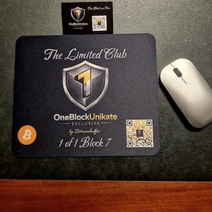 Könnte beinhalten: Eine schwarze Mausunterlage mit dem Text "The Limited Club" und "OneBlockUnikate Exclusive". Sie zeigt ein Schildlogo mit einer goldenen "1" und einem Bitcoin-Symbol. Eine weiße Computermaus und eine Visitenkarte sind ebenfalls vorhanden.