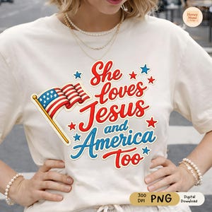 Puede incluir: Camiseta color crema con la frase "She loves Jesus and America Too" en letras rojas y azules, junto con un gráfico de la bandera estadounidense. El diseño incluye estrellas y es una declaración patriótica y religiosa.