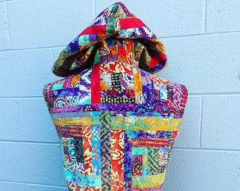 May include: A sleeveless hooded vest made from colorful patchwork fabric. The fabric is a mix of red, orange, yellow, green, blue, purple, and brown. The vest has a hood and a zipper closure.
