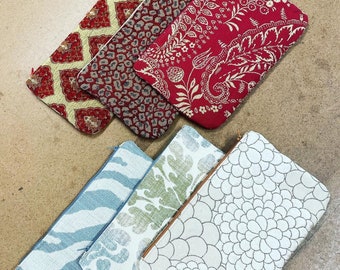 May include: Five different fabric zippered pouches with various patterns. The pouches are in shades of red, blue, and white. The patterns include floral, geometric, and abstract designs.