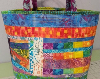 May include: A colorful patchwork tote bag with a blue, green, orange, red, purple, and white design. The bag has two straps and a zipper closure.