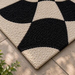 May include: A rectangular doormat featuring a high-contrast geometric pattern of interlocking black and cream-colored circles. The surface has a coarse, textured pile construction, creating a repeating pattern of curved shapes across the entire mat.