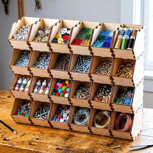 May include: A light-colored wooden storage unit with twenty-four open-front compartments arranged in four rows and six columns. The bins are filled with various craft supplies including metal hardware, colorful beads, spools of thread, and small dice.
